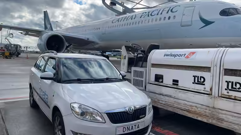Dienstvoertuigen op airside Schiphol naast een Cathay Pacific-vliegtuig